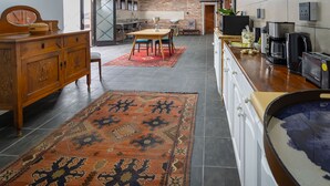 Una cocina moderna con comedor, que incluye un mueble de madera, una cafetera y un tapete grande.