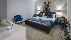 Un dormitorio con cama, una silla, un escritorio y una mesita de noche.