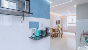 Une cuisine moderne équipée d’un four à micro-ondes, d’un grille-pain, d’une bouilloire et d’une machine à café, le tout placé sur un plan de travail. Un coin repas avec une table et des chaises est également disponible.