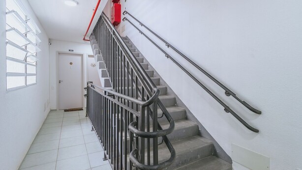 Un escalier avec des rampes en métal, une porte blanche et une fenêtre avec des stores.
