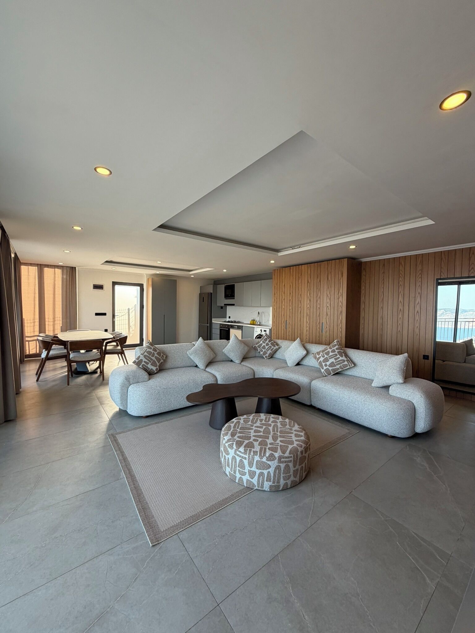 Una sala de estar moderna con un sofá modular, una mesa de centro y un comedor con mesa y sillas.