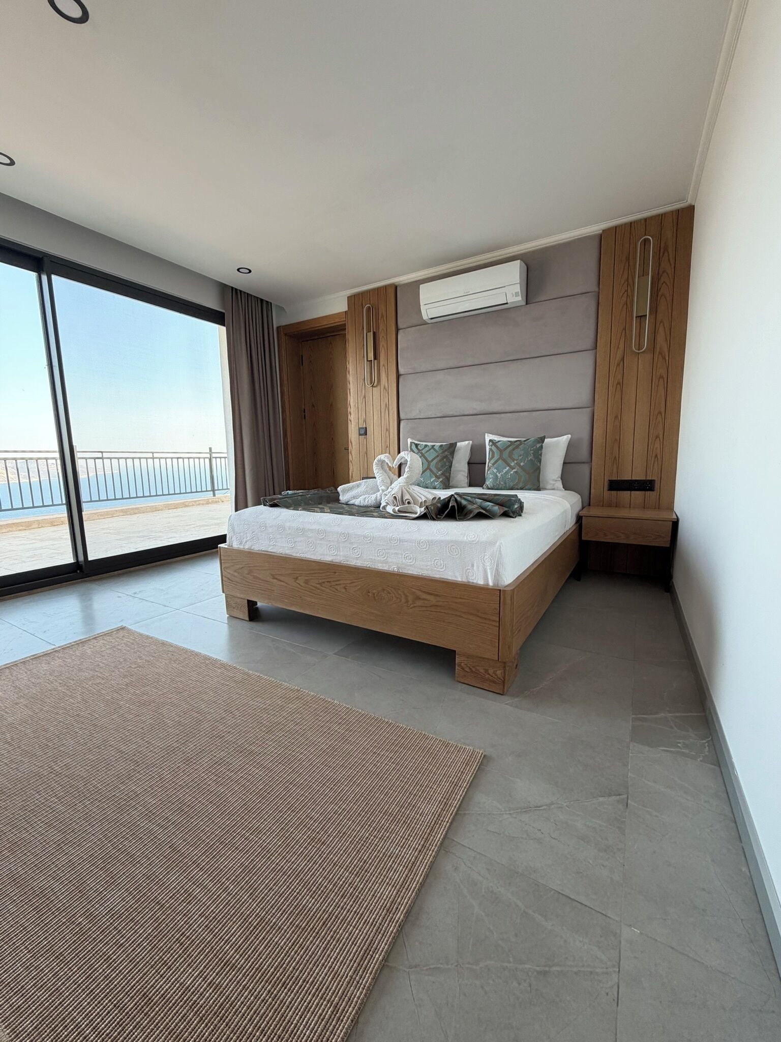 Un dormitorio moderno con una cama grande, cabecera de madera y vistas al mar.