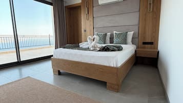 Un dormitorio moderno con una cama grande, cabecera de madera y vistas al mar.