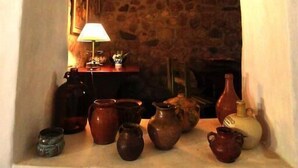 Ένα τζάκι από πέτρα με ένα ράφι όπου είναι τοποθετημένα κεραμικά αντικείμενα.