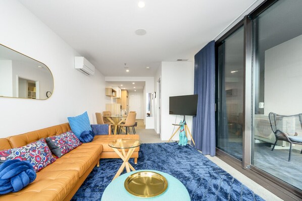 A modern living room with a sofa, coffee table, and a large window.