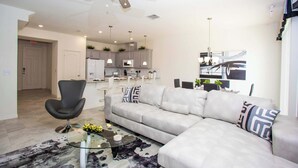 A modern living room with a grey sofa, black armchair, and a glass coffee table. - Family Friendly 4Bd Townhome GameRoom near Disney 5149 (Kissimmee)