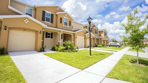 A row of two-story houses with beige exteriors, white trim, and a clear blue sky. - Family Friendly 4Bd Townhome GameRoom near Disney 5149 (Kissimmee)