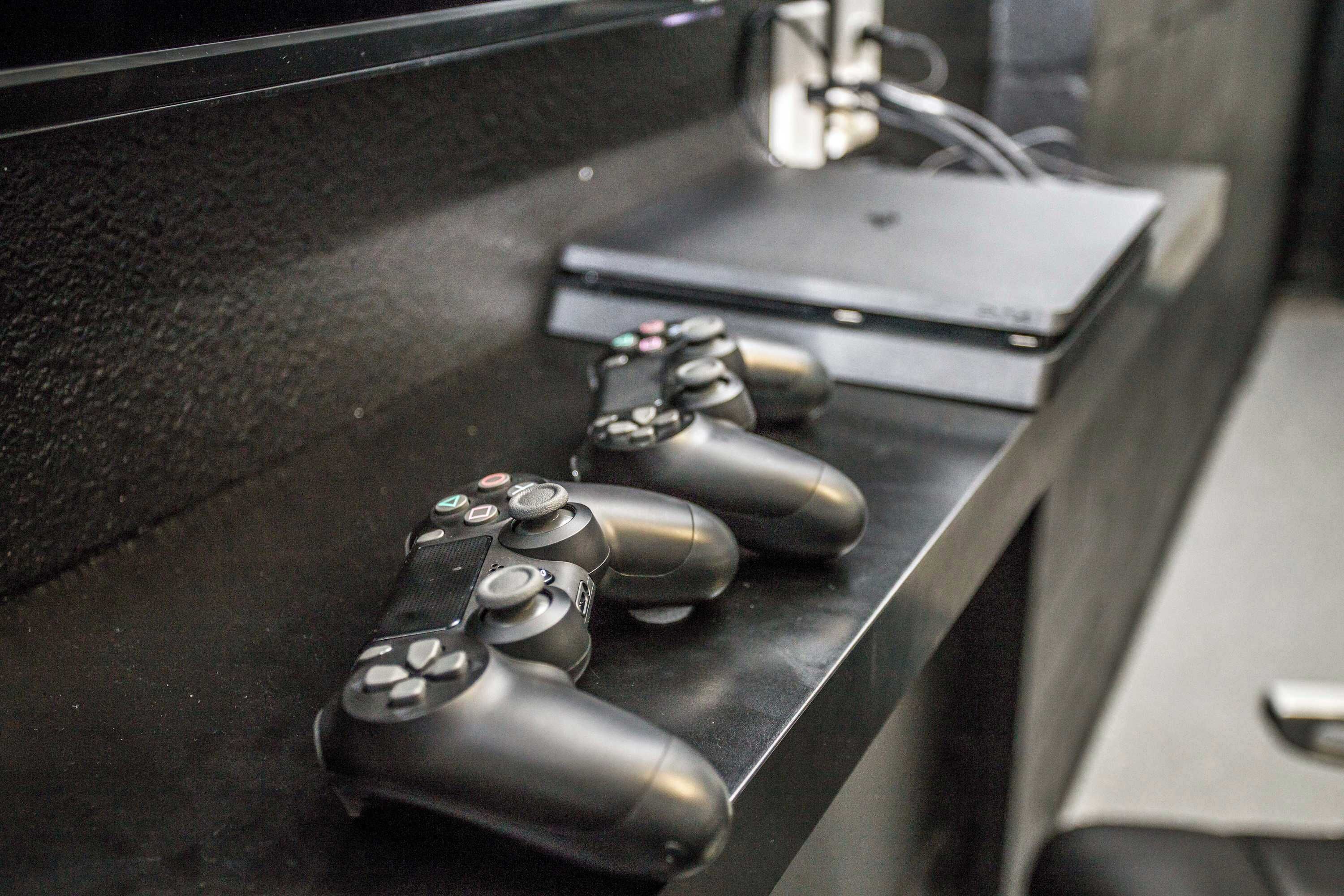 A row of black gaming controllers on a black surface, likely a gaming console or a gaming station.