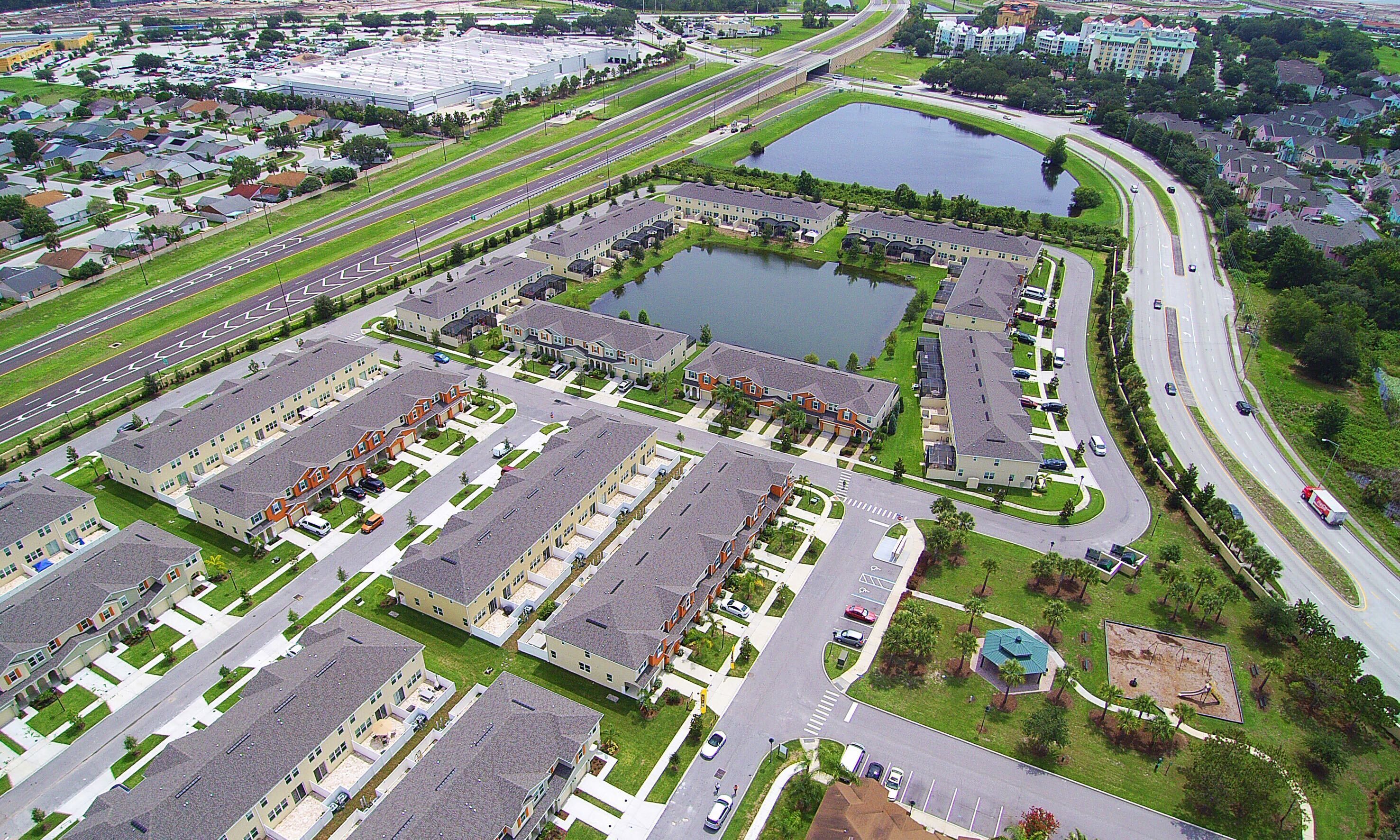 An aerial view of a residential area with multiple apartment buildings, roads, and a large body of water.