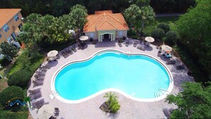 Luchtbeeld van een resort met een zwembad, ligbedden en palmbomen.
