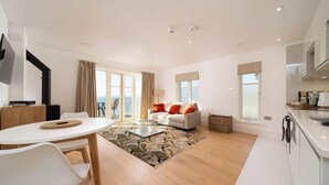 A modern living room with a sofa, a dining table, and a kitchen area. - Romantic Sea View Escape at Tors Park - Terrace (Lynmouth)