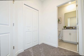 A hallway with white doors, a bathroom with a toilet, and a sink.