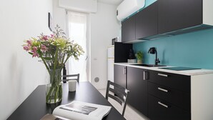 A modern kitchen with black cabinets, a white countertop, and a teal backsplash. - Italianway Comfort - Rembrandt 58 (Milan)