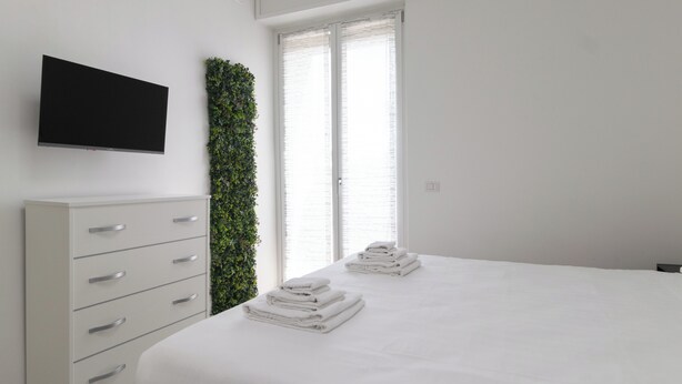 A modern bedroom with a bed, a TV mounted on the wall, and a vertical garden. - Italianway Comfort - Rembrandt 58 (Milan)