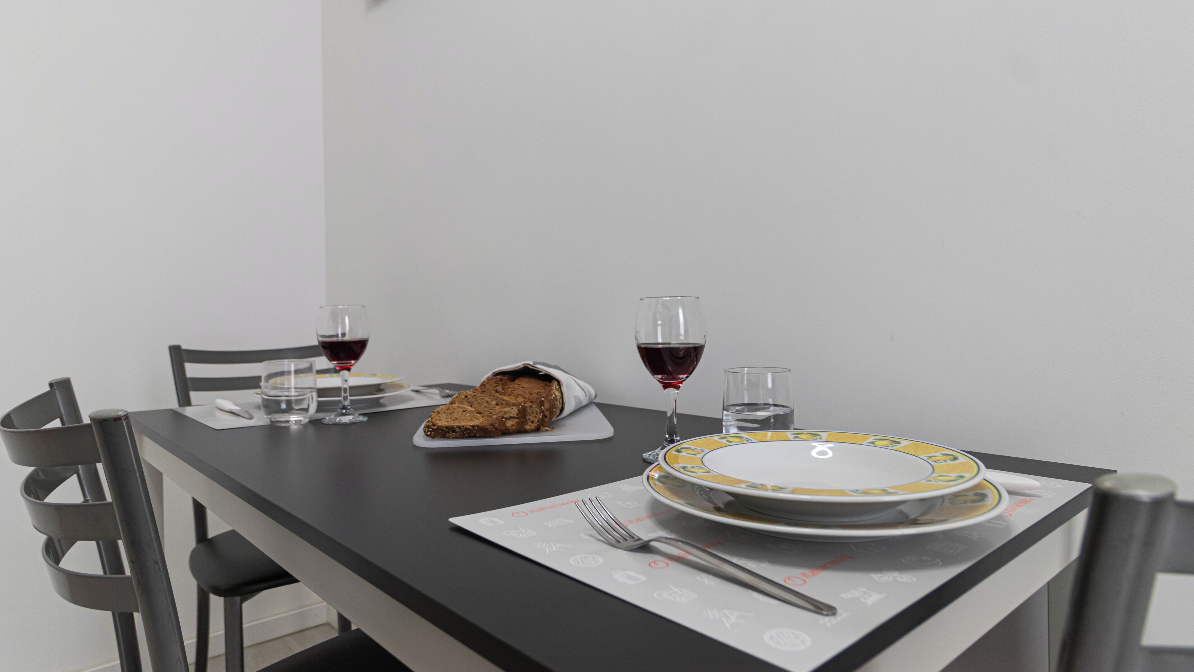 Une table à manger avec un pain, deux verres à vin et une assiette avec une fourchette.