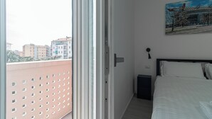 A bedroom with a bed, a painting, a door, and a view of buildings outside. - Italianway Comfort - Rembrandt 58 (Milan)