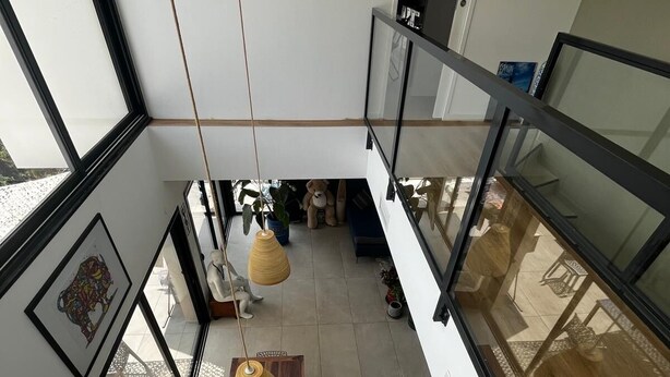 Ein modernes Interieur mit einem Holztisch, Pendelleuchten und einer Treppe, die in einen oberen Bereich führt.