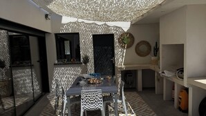 Eine Außenpatio mit Tisch und Stühlen, einem gemusterten Teppich und einer dekorativen Decke.