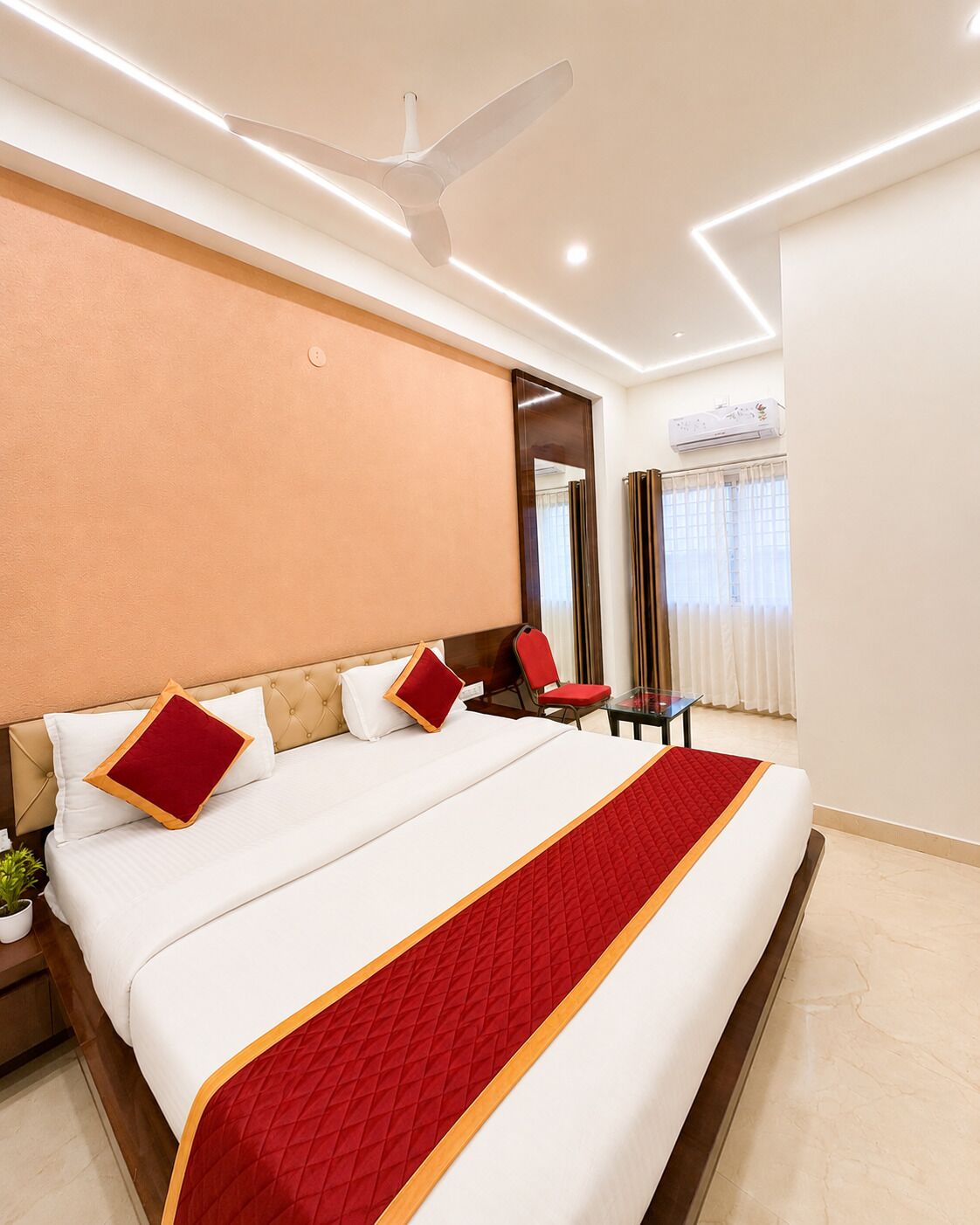 Habitación de hotel con una cama grande, un ventilador de techo, un escritorio y un espejo.