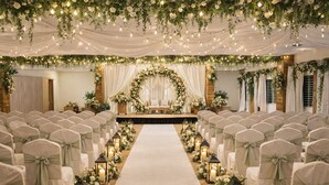A wedding venue with rows of chairs, a central aisle, and floral decorations. - Bhadrachalam Nest Inn (Mysore)