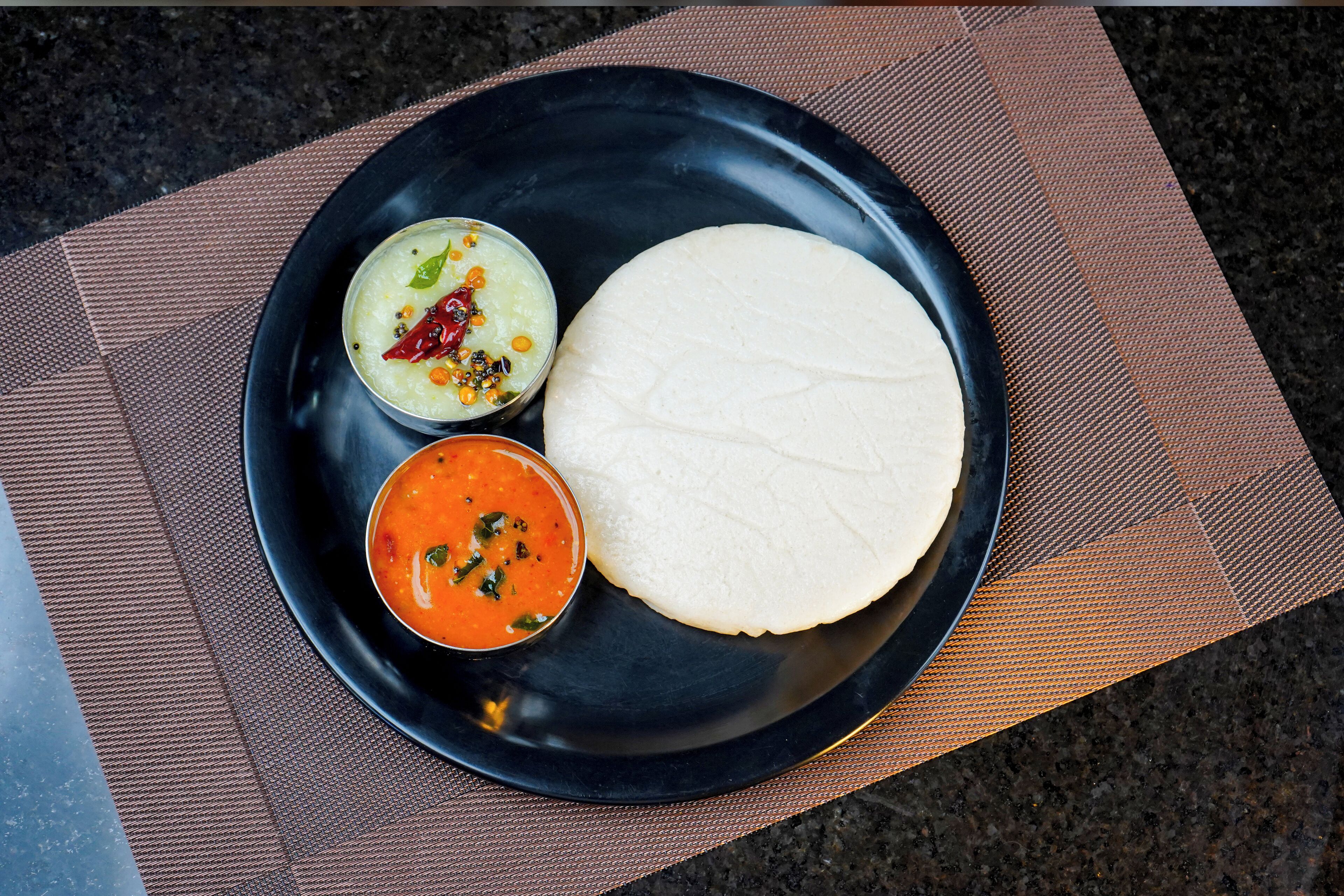 Un piatto con una piadina, una ciotola di zuppa e una piccola ciotola di sottaceto.