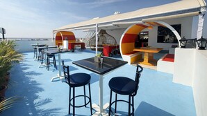 An outdoor deck with tables and chairs, a seating area with cushions, and a view of the sea. - Bhadrachalam Nest Inn (Mysore)