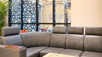 A modern living room with a sectional sofa, a glass coffee table, and a decorative screen with geometric patterns.