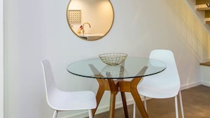 A modern interior with a glass table and white chairs, a round mirror on the wall, and a wooden staircase. - Inventors` Loft - Luxury, Upscale, Quiet 2BD! (Philadelphia)