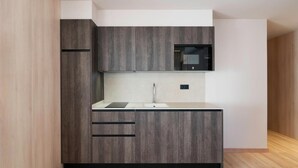 Una cocina moderna con armarios de madera oscura, encimera blanca y microondas empotrado.