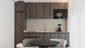 Una cocina moderna con armarios de madera oscura, un microondas y un lavabo. Hay una mesa redonda con dos sillas frente a ella.