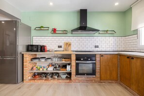 A kitchen with a refrigerator, microwave, oven, and various kitchen utensils.