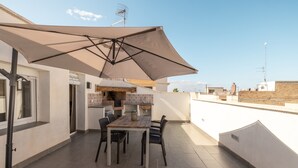 An outdoor patio with a table and chairs, a large umbrella, and a view of the city. - Apartment in Deltebre Casa Fotostudi37 (Deltebre)