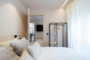 Une chambre d’hôtel comprenant un lit, une télévision, un bureau avec une chaise et une armoire.