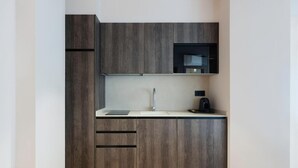 Eine moderne Küche mit dunklen Holzschränken, einer Edelstahlspüle und einer schwarzen Mikrowelle.