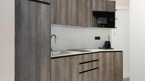 Una cocina moderna con armarios de madera, microondas, fregadero y cafetera.