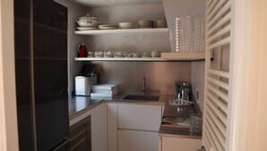 Una cucina compatta con forno a incasso, macchina del caffè e lavello.