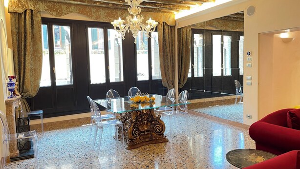 Zona pranzo con tavolo e sedie in vetro, un centrotavola decorativo e un lampadario.