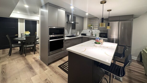 Una cucina moderna con isola centrale, elettrodomestici integrati e zona pranzo con tavolo e sedie in legno scuro.