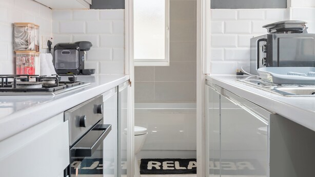 Una cocina moderna con armarios blancos, estufa a gas y microondas.