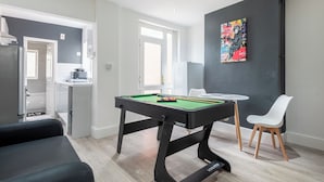 Una sala de estar moderna con una mesa de billar, un sofá y una mesa de comedor con sillas.