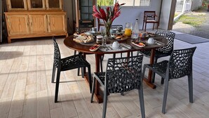 Un comedor con una mesa y sillas de madera, un armario con puertas de cristal y vistas a una casa a través de una ventana.