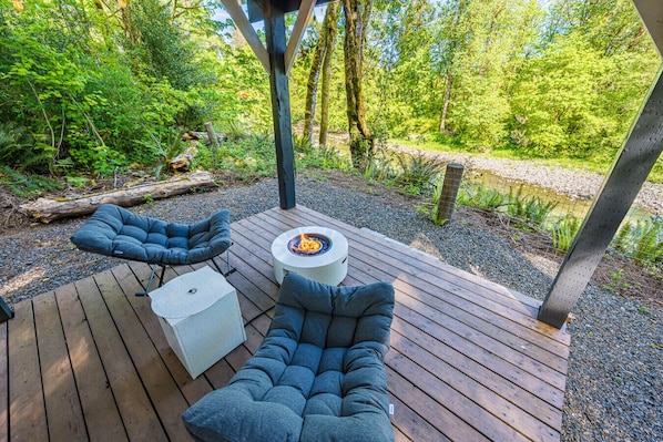 Une terrasse extérieure dotée de deux coins salon confortables et d’un foyer central.