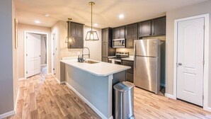 A modern kitchen with a central island, stainless steel appliances, and pendant lighting. - Private Riverfront home w/ Hot tub, central to ONP (Beaver)
