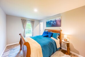 Une chambre à coucher avec un lit en bois, une fenêtre avec des rideaux, un tableau au mur et une lampe de chevet.