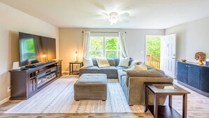 A living room with a television, sofa, ottoman, and a ceiling fan. - Private Riverfront home w/ Hot tub, central to ONP (Beaver)