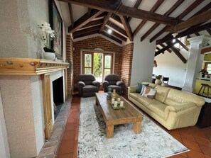 Ein Wohnzimmer mit Kamin, zwei Sesseln, einer Couch und einem Couchtisch.