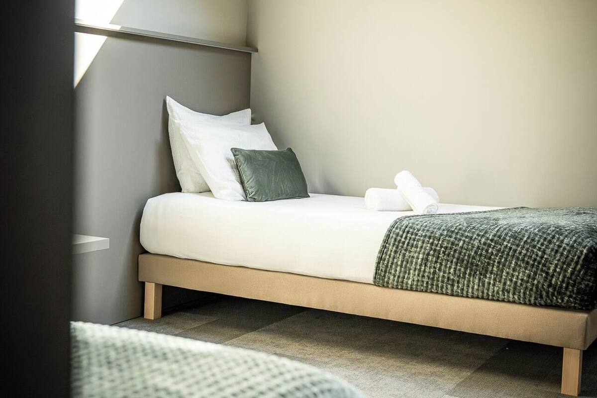 Une chambre avec un puits de lumière, un lit avec des oreillers et une couverture.