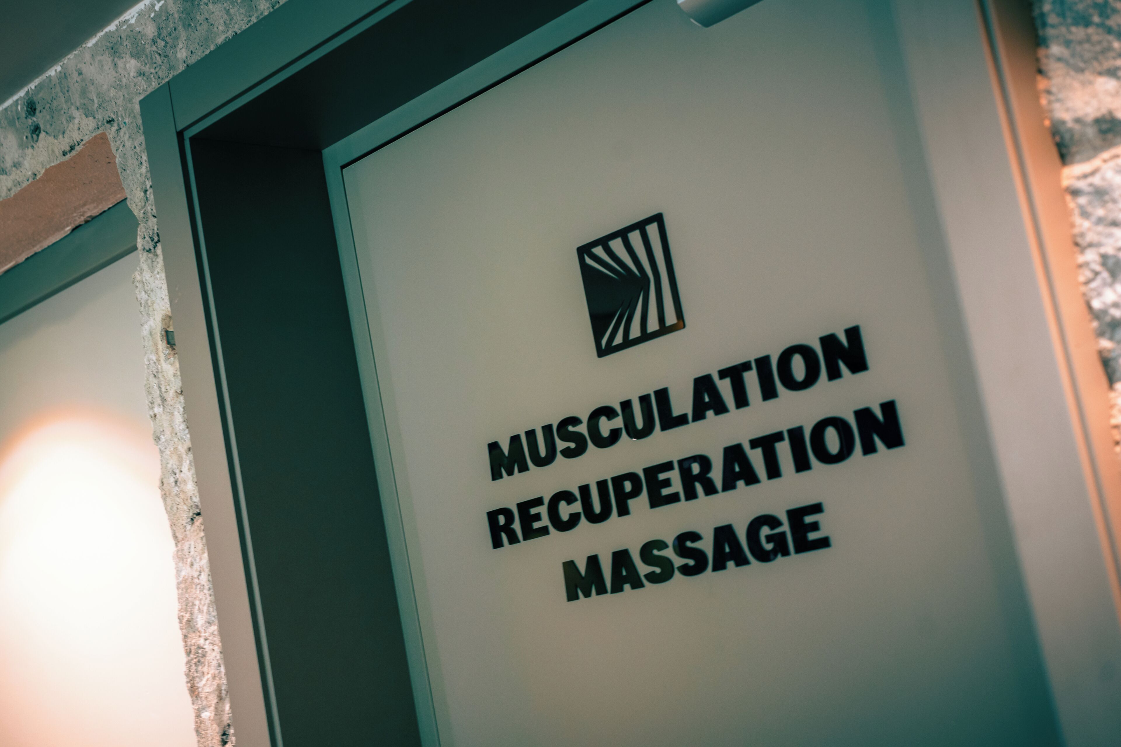 Eine Wand mit einem Schild, auf dem 'MUSCULATION RECOVERY MASSAGE' steht.