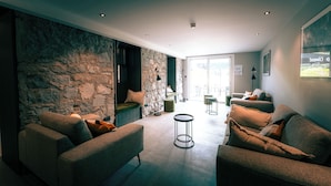 A modern living room with a stone wall, two sofas, a round coffee table, and a large window. - L'Echappée Vosgienne (Gérardmer)
