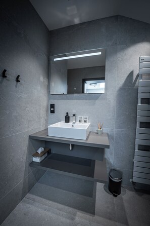 Ein modernes Badezimmer mit Waschbecken, Spiegel und Handtuchhalter.